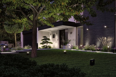 Moderne Außenbeleuchtung mit schwarzen LED-Strahlern beleuchtet Gartenweg und Hausfassade bei Nacht