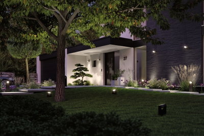 Modernes Haus mit schwarzer Fassade und weißem Eingangsbereich beleuchtet von LED-Außenleuchten im Garten