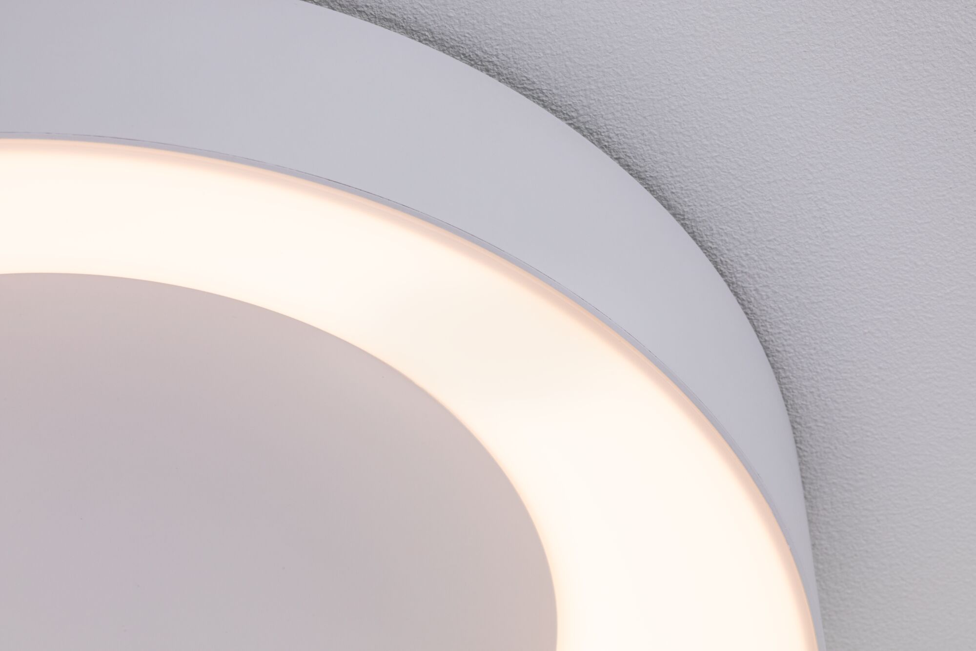 Close-up of white round LED ceiling light with warm white glow and modern design