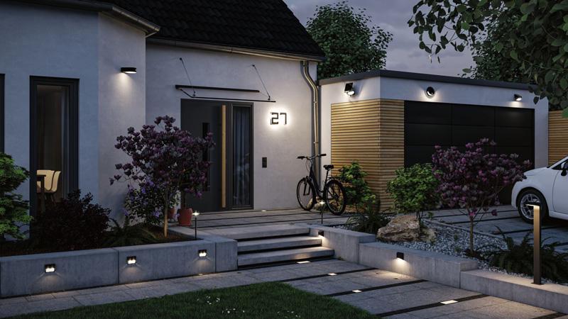 Maison moderne avec éclairage extérieur solaire et lampes LED de chemin dans le jardin au crépuscule