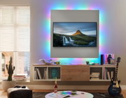 Wohnzimmer mit TV und buntem LED-Hintergrundlicht für moderne Ambientebeleuchtung und Smart Home Lichtsteuerung