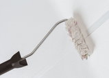 Paint roller with black handle and white fluffy roller cover for precise edge painting and wall finishing.