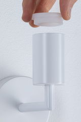 Hand holding white plastic cap above white metal wall lamp holder for LED light