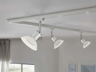 Three white metal LED ceiling spotlights on track system for modern room lighting