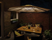 Beige outdoor parasol with integrated LED lighting above wooden garden table at night