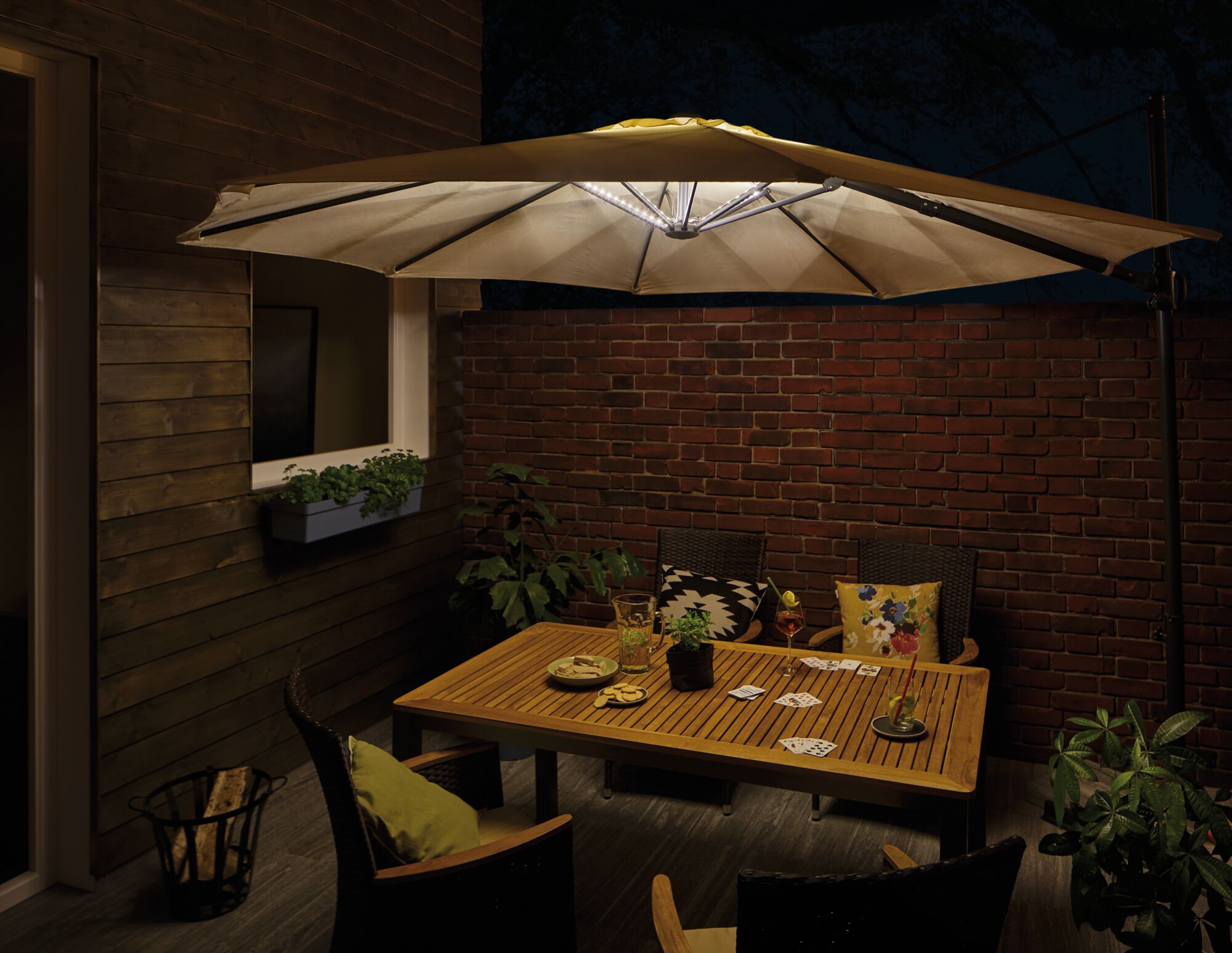 Parasol beige avec éclairage LED intégré au-dessus d'une table en bois dans un jardin la nuit