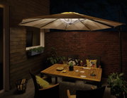 Parasol beige avec éclairage LED intégré au-dessus d'une table en bois dans un jardin la nuit