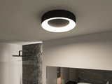 Ronde zwarte plafondlamp met warmwit LED-licht in moderne badkamer met stenen muur.