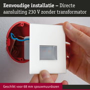 Hand plaatst witte wandcontactdoos met directe 230 V aansluiting zonder transformator in rode inbouwdoos