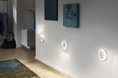 Drei runde LED-Wandleuchten mit warmweißem Licht an weißer Wand im modernen Wohnraum.