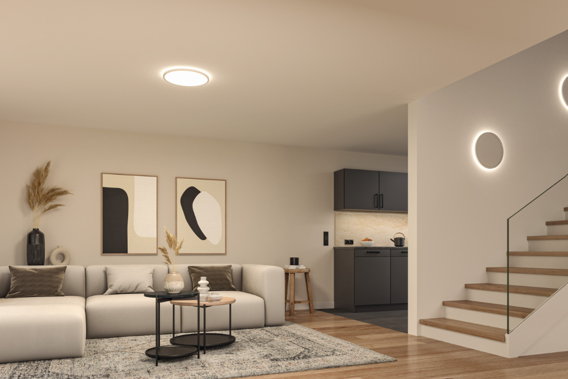 Rundes LED-Deckenpanel in warmweiß beleuchtet modernes Wohnzimmer mit Sofa und Treppe