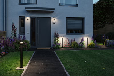 Moderne Außenbeleuchtung mit schwarzen Pollerleuchten und Wandlampen an Hausfassade und Gartenweg