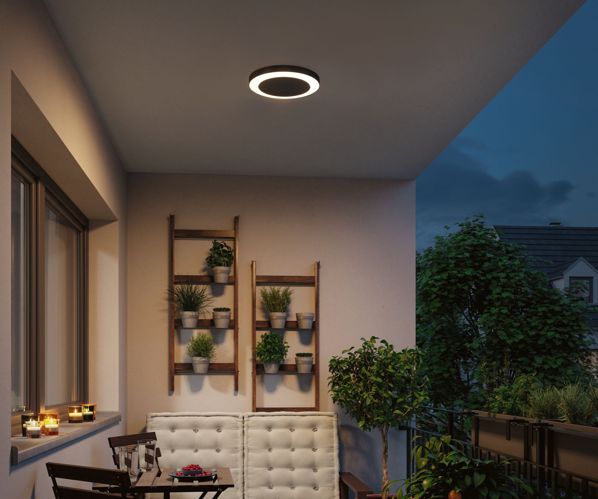 Plafonnier LED rond noir avec lumière blanche chaude sur balcon avec plantes et coin salon