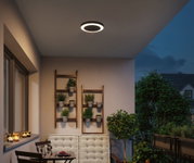 Plafonnier LED rond noir avec lumière blanche chaude sur balcon avec plantes et coin salon