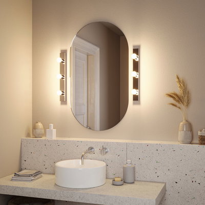 Moderne badkamer met ovale spiegel en twee warmwitte metalen wandlampen naast de wastafel.