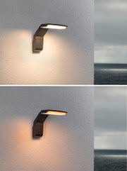 Moderne schwarze Außenwandleuchte aus Metall mit warmweißem LED-Licht an Hauswand mit Meerblick
