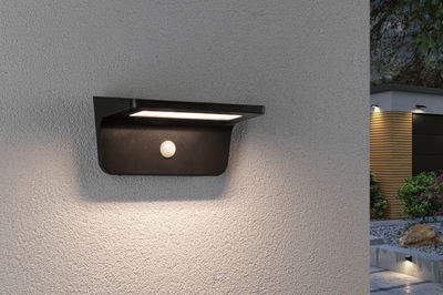 Black LED outdoor wall light with motion sensor on grey wall for modern garden lighting