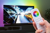 Hvid fjernbetjening med farvehjul styrer LED-bagbelysning på tv til stemningsbelysning