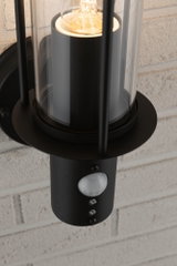 Sort metal udendørs væglampe med klart glas og indbygget bevægelsessensor til udendørs belysning
