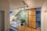 Modern living space with wooden floor, green leaf wallpaper, and black LED track lighting on ceiling