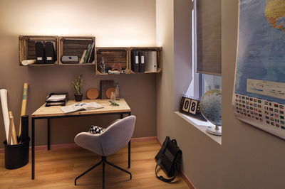 Espace de travail moderne avec bureau en bois, chaise grise et éclairage mural LED chaud pour bureau