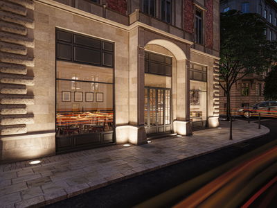 Außenbeleuchtung mit warmweißen Bodeneinbauleuchten an Sandsteinfassade eines Restaurants in der Stadt.