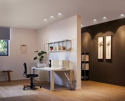 Modern office with white furniture and warm white LED downlights on ceiling for commercial lighting.