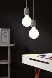 Zwei hängende LED-Glühbirnen mit grauen Metallfassungen vor schwarzem Hintergrund im modernen Arbeitszimmer