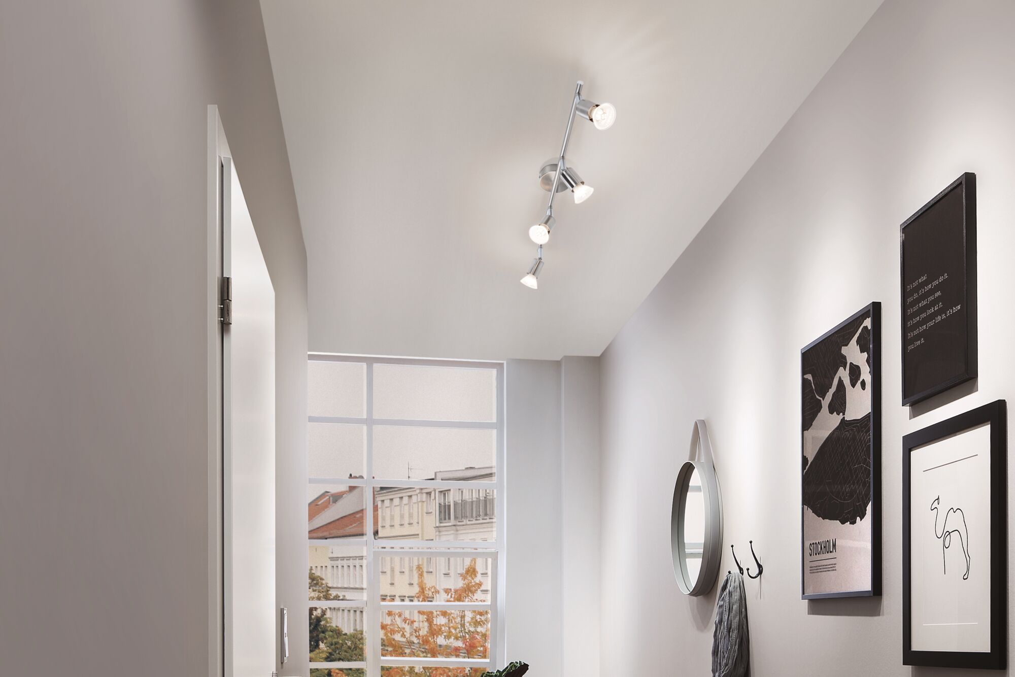 Moderne plafondspot van geborsteld aluminium met vier verstelbare lampen in gang met wanddecoratie.