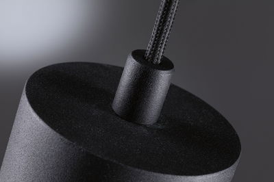 Close-up of black textured pendant lamp with fabric cord for modern lighting design