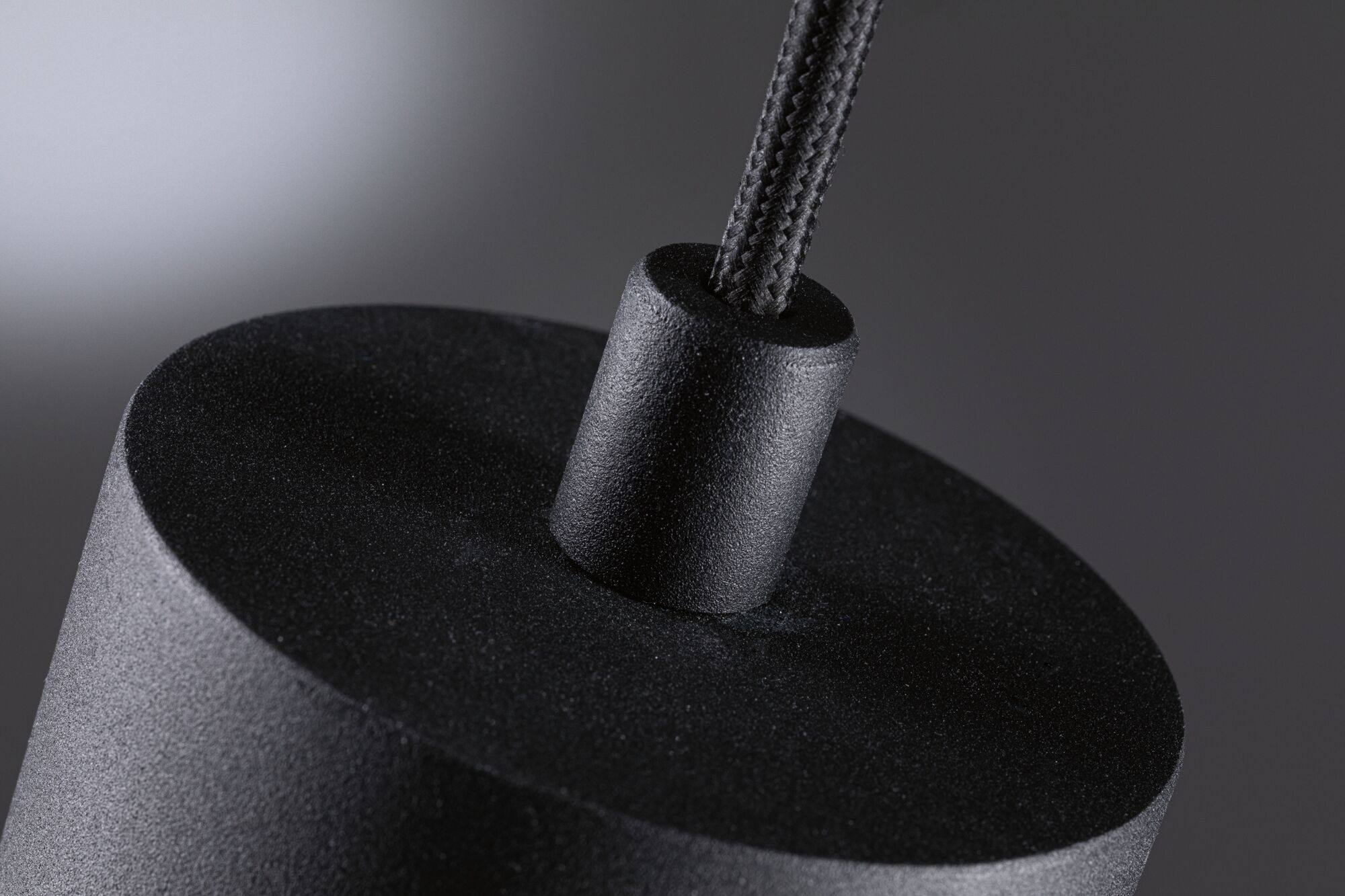 Close-up van zwarte, gestructureerde hanglamp met stoffen snoer voor moderne verlichting