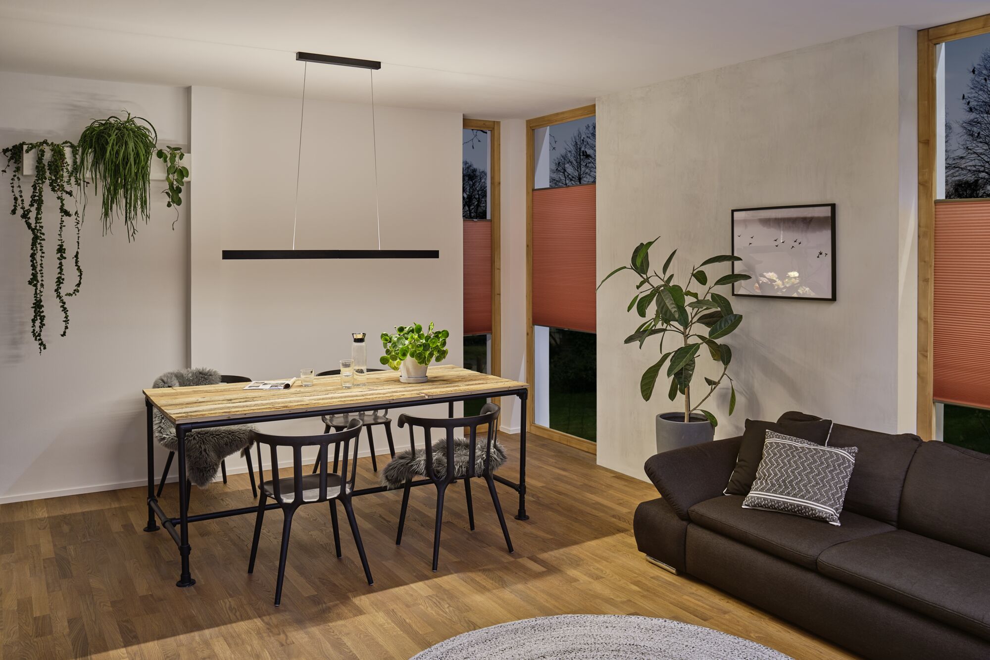 Moderner Essbereich mit Holz-Metall-Tisch, schwarzen Stühlen und minimalistischer Pendelleuchte in warmem Licht