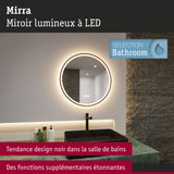 Miroir LED rond avec lumière chaude et vasque noire sur marbre vert dans une salle de bains moderne