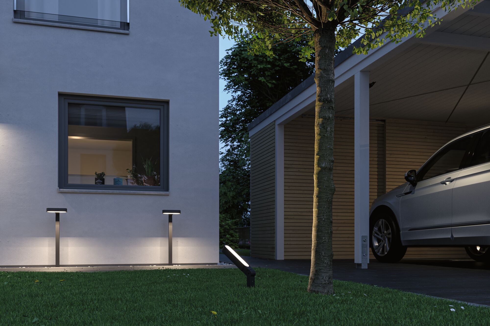 Moderne zwarte LED-buitenlampen verlichten huismuur en tuin met boom en carport in de schemering.