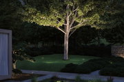 Garten mit beleuchtetem Baum und LED-Außenstrahlern auf grünem Rasen für stimmungsvolle Außenbeleuchtung.