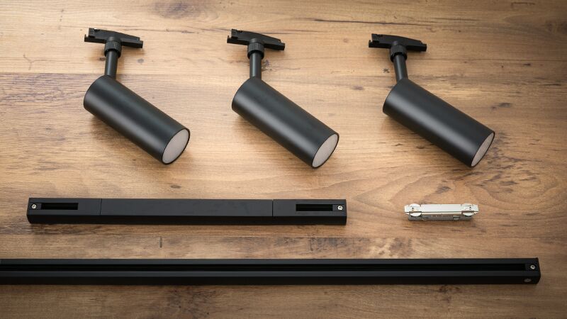 Trois spots LED URail noirs avec rails et connecteur sur table en bois pour installation d'éclairage flexible.