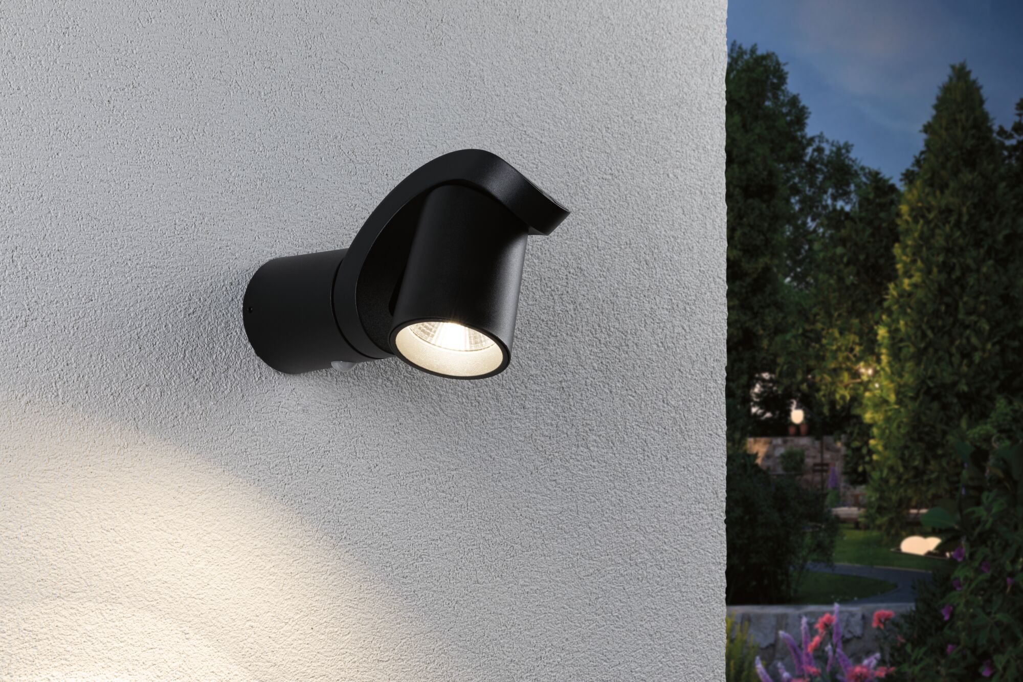 Schwarze Aluminium-Außenwandleuchte mit warmweißem LED-Strahler an weißer Wand im Garten.