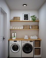 Moderne Waschküche mit weißen Waschmaschine und Trockner, Holzarbeitsplatte und geflochtenen Körben