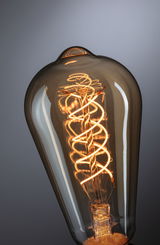 Close-up of vintage light bulb with spiral filament and brown glass for decorative lighting use