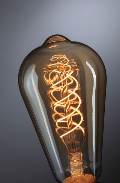 Close-up of vintage light bulb with spiral filament and brown glass for decorative lighting use