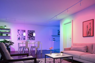 Moderne woonkamer met kleurrijke LED-verlichting, bank en eettafel in open ruimte