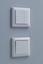 Two white plastic wall switches on blue wall, top with LED indicator, bottom classic design.