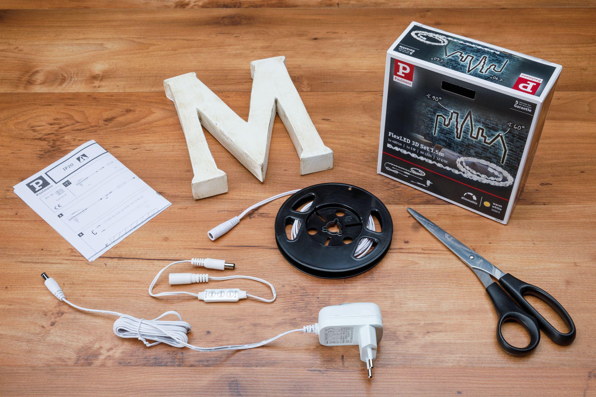 FlexLED 3D set met 5m warmwitte LED-strip, adapter, afstandsbediening en handleiding op houten tafel.