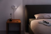 Moderne weiße LED-Wandleuchte aus Metall neben Bett mit Holztisch und Schlüssel