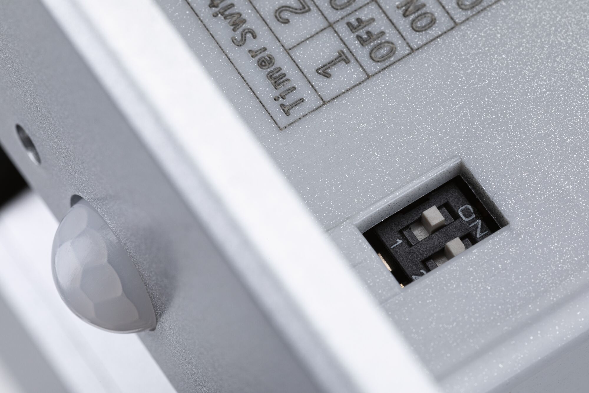 Close-up of grey plastic housing with DIP switch and sensor for light control