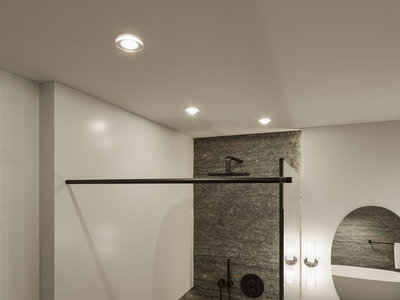 Modern bathroom with black fixtures and grey stone wall, illuminated by three recessed ceiling lights
