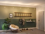 Cozy rattan papasan chair with cream cushion in modern hallway featuring green painted walls and patterned floor