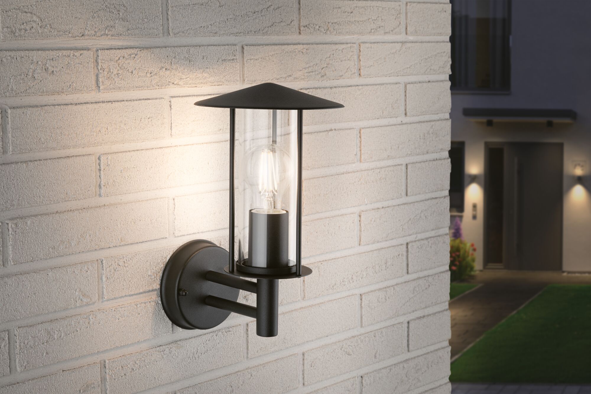 Sort metal udendørs væglampe med klart glas og synlig LED-pære til havebelysning.