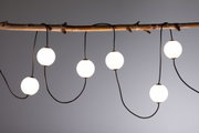 Moderne LED-Lichterkette mit weißen Kugeln an schwarzem Kabel, dekorativ an Holzast hängend