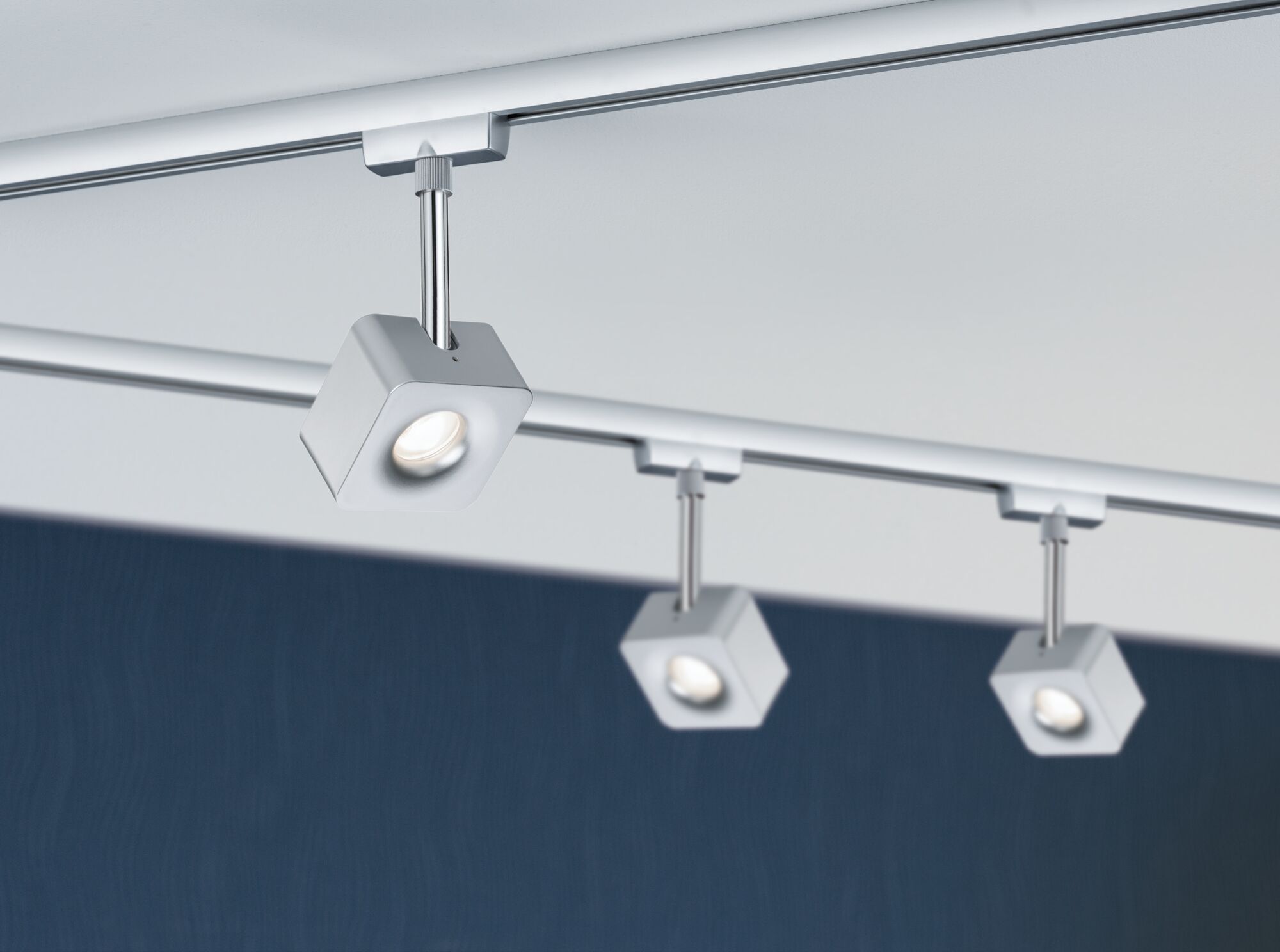Moderne witte LED-railverlichting met drie verstelbare vierkante metalen spots voor woonruimtes.